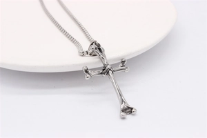 Detail of vintage bone-shaped cross pendant in silver on a square pearl chain
