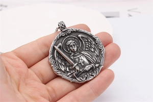 Macro detail of retro silver archangel pendant with sword and cross relief texture