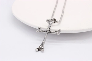 Macro detail of retro silver bone cross pendant with vintage oxidized finish on steel chain