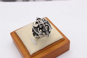 Gothic skull ring featuring flame patterns on a beige velvet display case stand
