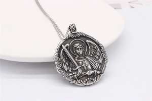 Macro shot of retro steel pendant showing an embossed winged angel with a sword