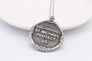 Detail of vintage Archangel St Michael pendant necklace with intricate scroll patterns