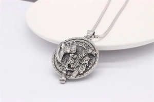Vue détaillée du pendentif viking avec hache et corbeau, runes nordiques sur chaîne acier