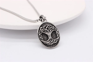 Detailed relief of vintage Tree of Life steel pendant necklace on a ceramic background