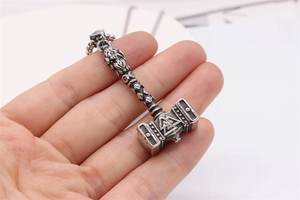 Gros plan du pendentif Mjölnir vintage avec symbole Valknut tenu en main