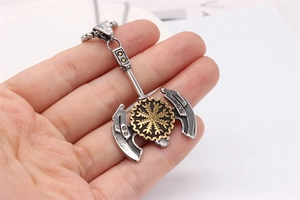 Détail du pendentif hache viking avec symbole Vegvisir doré tenu à la main