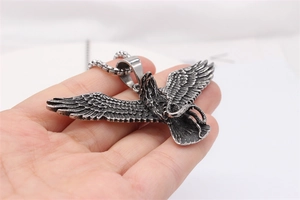 Detail of hand-held vintage eagle pendant with snake in titanium steel on box chain