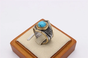 Macro view of retro feather ring with blue turquoise stone and golden bead details