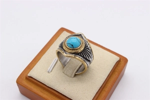 Macro detail of retro feather titanium steel ring with turquoise inlay and gold trim