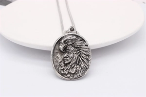 Gros plan du pendentif aigle et chef indien rétro en argent sur un plateau blanc