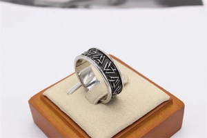 Macro detail of vintage Viking Valknut pattern engraved on a men's steel ring band