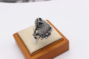 Macro shot of owl ring showing vintage texture and detailed feather engraving on metal