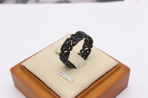 Macro shot of black Celtic knot cutout ring on a beige velvet stand with wooden base