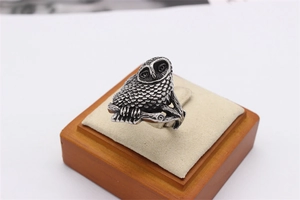 Detailed close-up of retro silver owl ring featuring intricate feather texture on wood stand