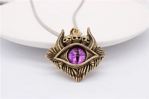 Makroaufnahme von Gothic Evil Eye Anhänger mit Totenköpfen und Federn in Gold-Optik