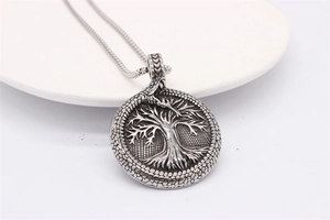 Macro detail of Tree of Life and Ouroboros pendant on silver steel snake chain