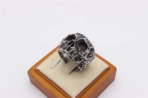 Detail of vintage skull ring with oxidized texture on a beige jewelry display