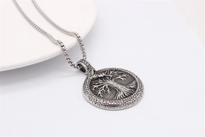 Macro detail of vintage silver Tree of Life pendant with solid box chain on white base