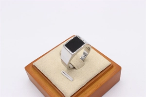 Detail view of a vintage men's stainless steel ring with black rectangular inlay on a display stand