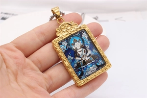Detail of vintage gold-plated stainless steel pendant with Buddhist deity painting