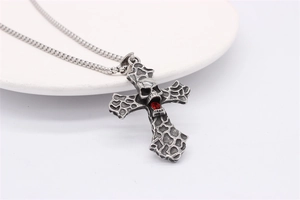 Detailed shot of gothic skull cross pendant with red zircon and vintage steel chain