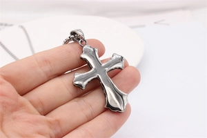 Macro shot of retro stainless steel cross pendant with vintage finish held in hand