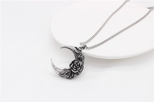 Détail macro du pendentif lune gothique en argent avec relief rose sur assiette blanche
