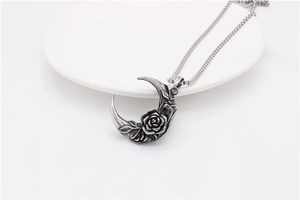 Détail du pendentif lune en argent vintage avec motifs roses et finition oxydée