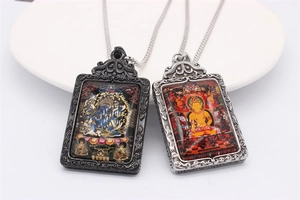 Detail of vintage Thangka Buddhist pendants in black and silver stainless steel frames