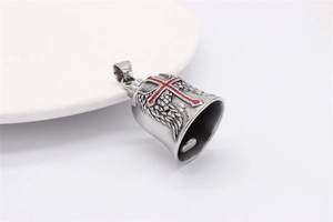 Macro detail of retro bell pendant with red cross and wings on white ceramic plate