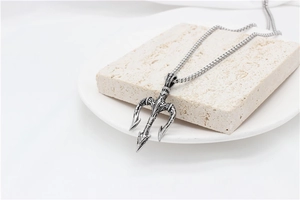 Macro detail of retro trident pendant with embossed textures and a round box chain