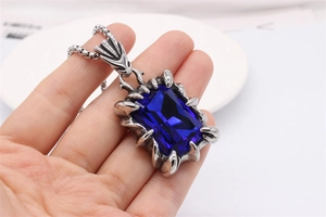 Détail du pendentif en pierre bleue rectangulaire avec griffes de dragon et chaîne en acier