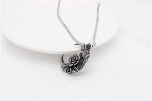 Gros plan du pendentif lune en argent vintage avec relief de rose et chaîne en acier