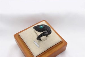 Detailed close-up of retro steel feather ring with turquoise stone inlay on a display