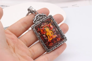Detail view of vintage zodiac deity pendant with Thangka Buddha art and carved steel frame