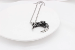 Vue détaillée du collier avec pendentif rose et lune en acier vintage sur une céramique blanche