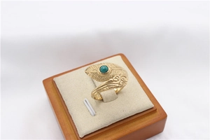 Macro detail of retro gold feather ring with round turquoise stone on display stand