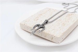 Macro shot of silver Poseidon trident pendant with vintage texture on a stone stand