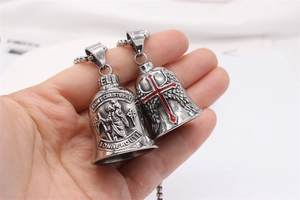 Detail of vintage steel bell pendant with saint engraving and red cross angel wings