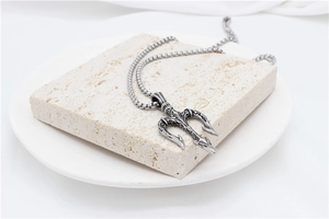 Macro shot of vintage silver trident pendant with oxidized details on a square box chain