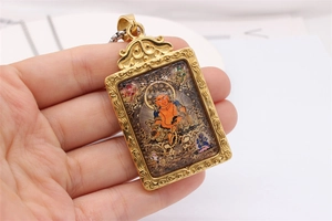 Detail of a golden zodiac pendant with embossed filigree and orange Thangka style deity