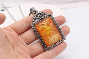Macro detail of yellow Jambhala Buddhist pendant with vintage silver steel frame