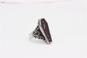 Detailed close-up of gothic mummy coffin ring with purple background and skull relief