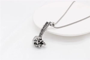 Detailed view of punk skull and spine steel pendant with vintage finish on a square chain