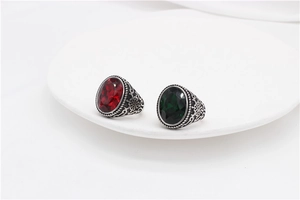 Macro shot of retro stainless steel rings with red and green oval gems and floral engravings