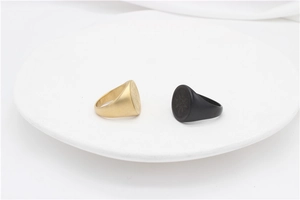 Detail of vintage compass signet rings in matte black and gold finishes on a white plate