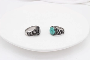 Detail of vintage steel rings with oval turquoise and black stones on white display
