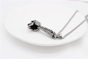 Detailed macro view of vintage silver skull and spine pendant with box chain on white tray