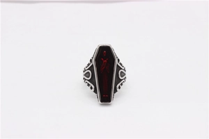 Detailed macro view of punk gothic coffin ring with red human figure and floral relief