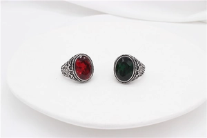 Detail view of vintage titanium steel rings with red and green oval gemstones and filigree